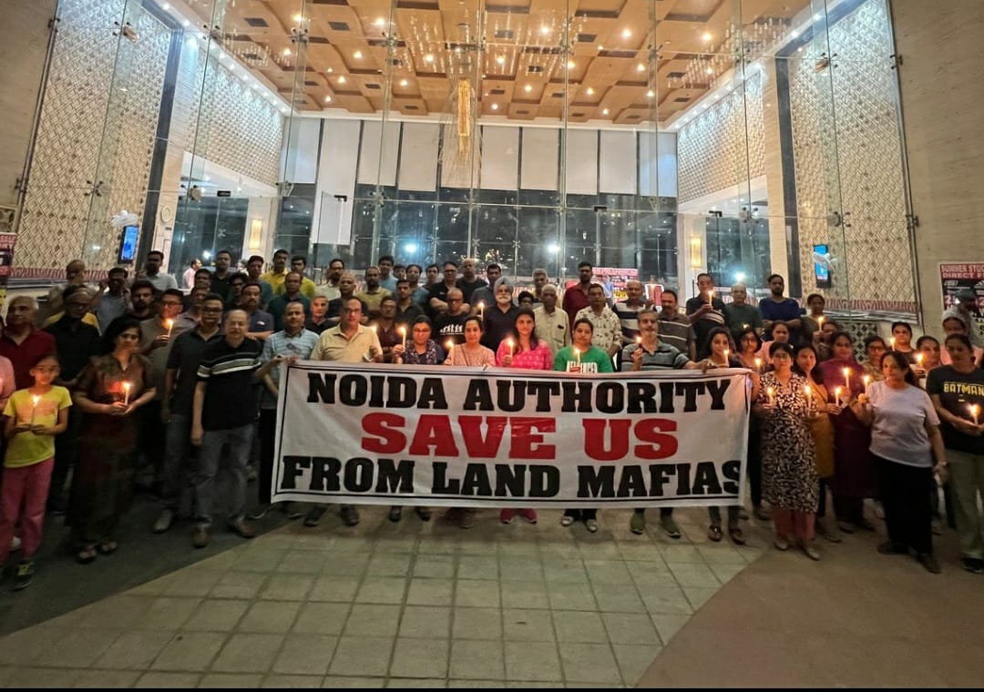 महागुन मॉडर्न के निवासियों का आठवें सप्ताह भी एओए के खिलाफ सत्याग्रह जारी, निवासियों ने की अपील भू माफिया से बचाएं